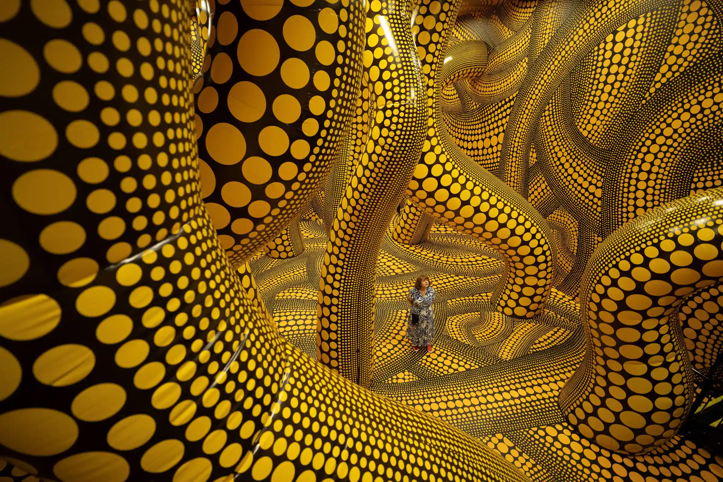 Une femme admire une œuvre d'art intitulée « The Hope of the Polka Dots Buried in Infinity Will Eternally Cover the Universe » qui figure dans une exposition de l'artiste japonaise Yayoi Kusama intitulée « You, Me and the Balloons » dans la galerie Aviva Studios à Manchester, dans le nord-ouest de l'Angleterre.